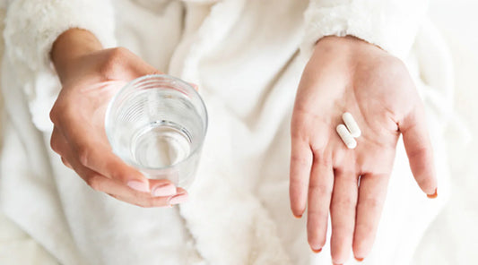 tablests in woman hand along with glass of water
