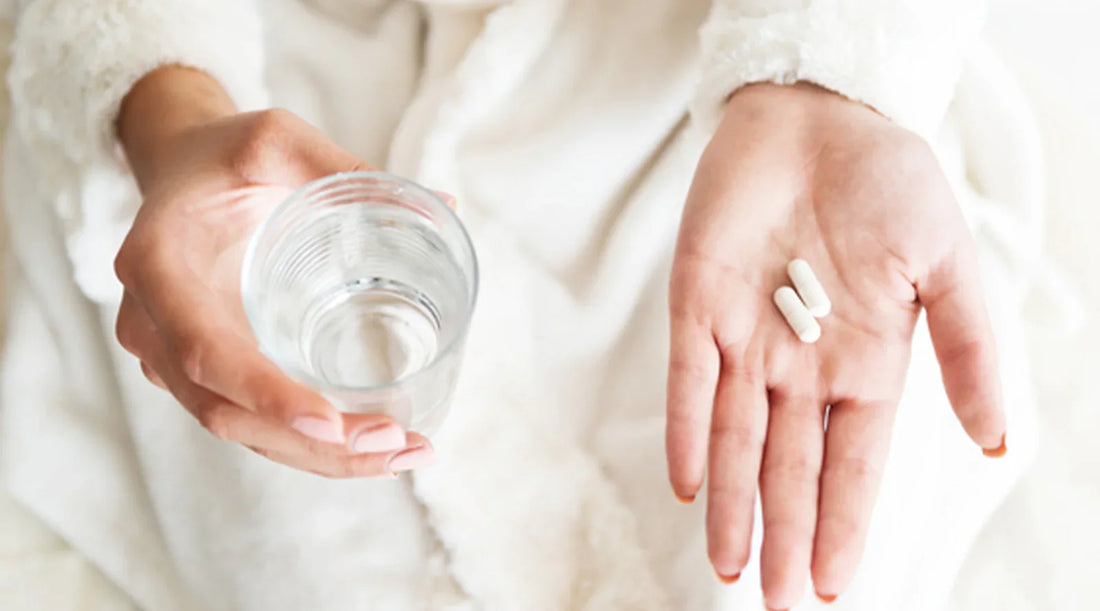 tablests in woman hand along with glass of water